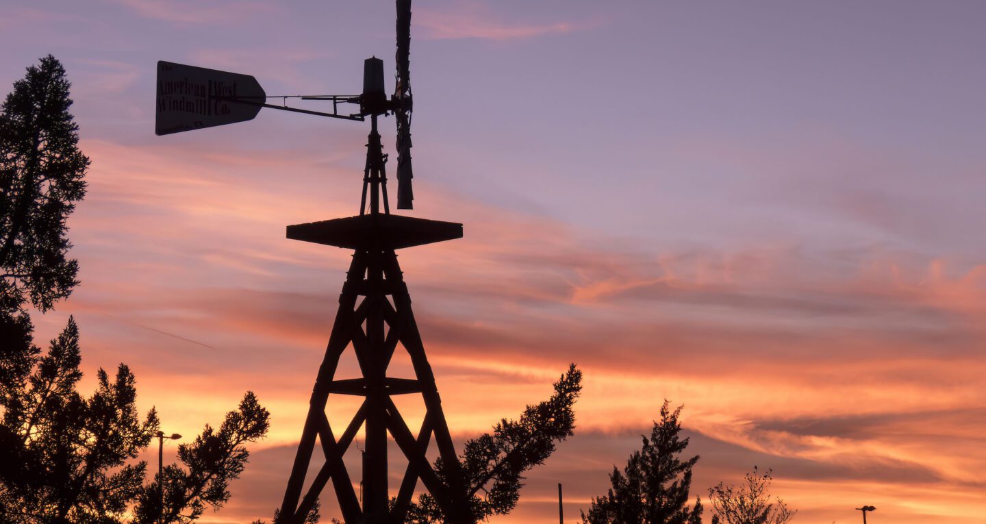 Colorful sunset silhouetting a decorative windmill near our Winslow hotel