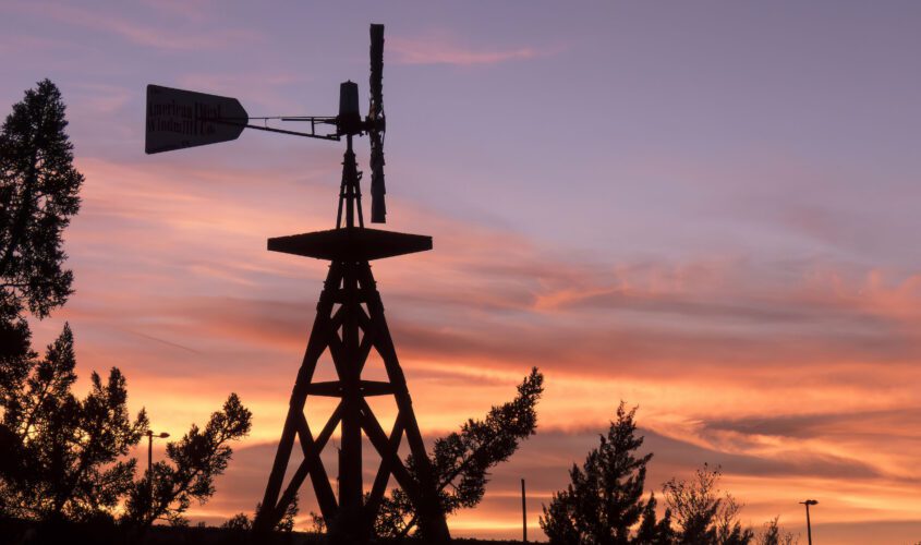 Colorful sunset silhouetting a decorative windmill near our Winslow hotel