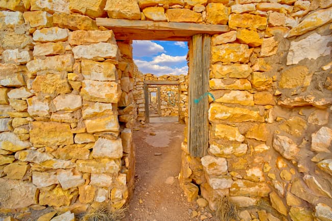 a doorway in a stone wall with a sky in the background