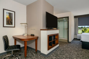 a hotel room with a desk, chair and television