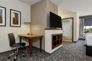 a hotel room with a bed, desk and television