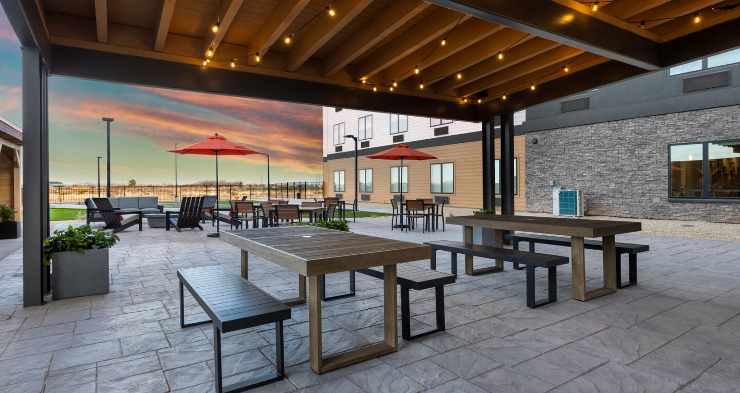 a patio with tables and umbrellas and a view of the ocean