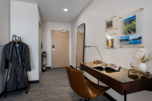 a room with a desk, chair, coat rack and mirror