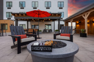 a fire pit on a patio with chairs and an umbrella