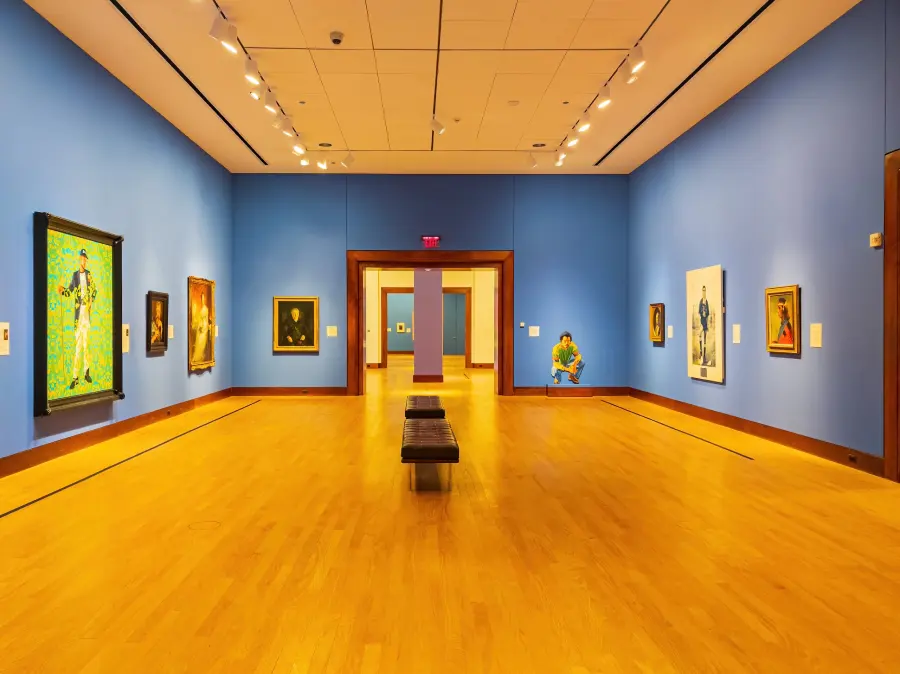 Paintings hang on blue walls in a bright art museum, one of many fun things to do in oklahoma city.