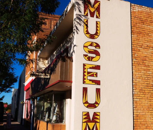 A museum building with a prominent sign on the side, featuring the word "MUSEUM" in large red and yellow letters against a white background.