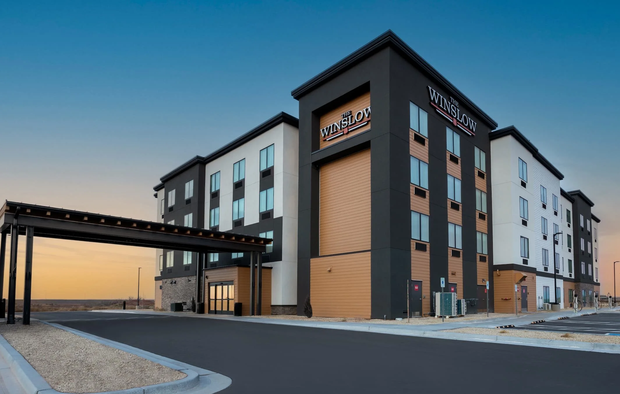 A multi-story hotel building with a sign reading "WINSLOW" in large letters, set against a blue sky.