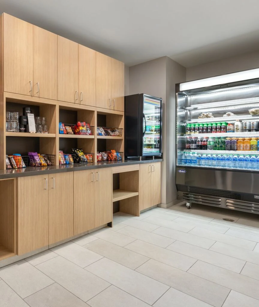 A hotel market with a refrigerator and shelves stocked with snacks and drinks.