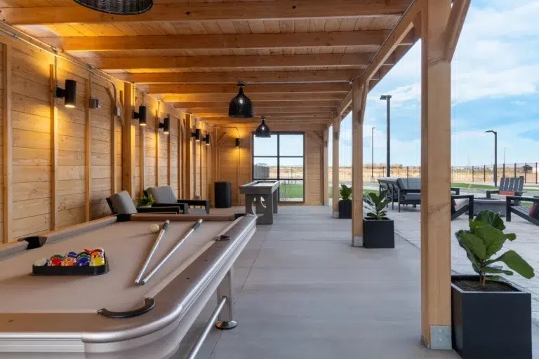 outdoor games area with a pool table, lounge chairs, and a large window.