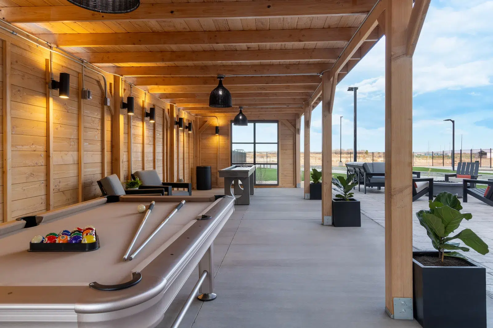 outdoor games area with a pool table, lounge chairs, and a large window.